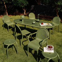 Green outdoor dining set with ribbed patterns on chairs and table, complemented by a lush grass backdrop.