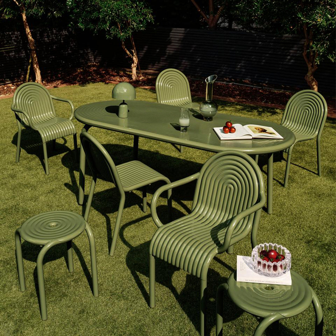 Green outdoor dining set featuring ribbed patterns on chairs and table, complemented by a grassy background.