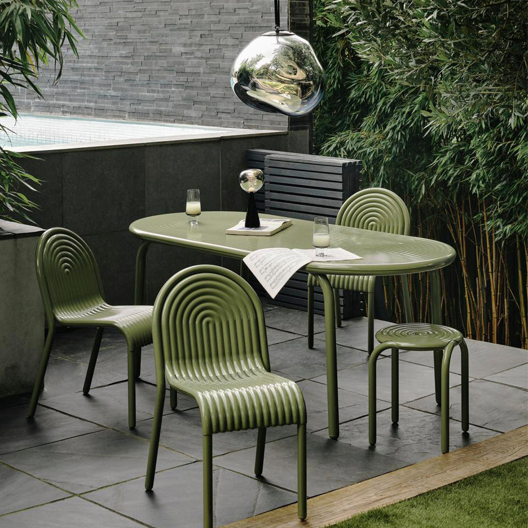 Green ribbed dining set with a sleek oval table and matching chairs, surrounded by bamboo and grey stone accents.