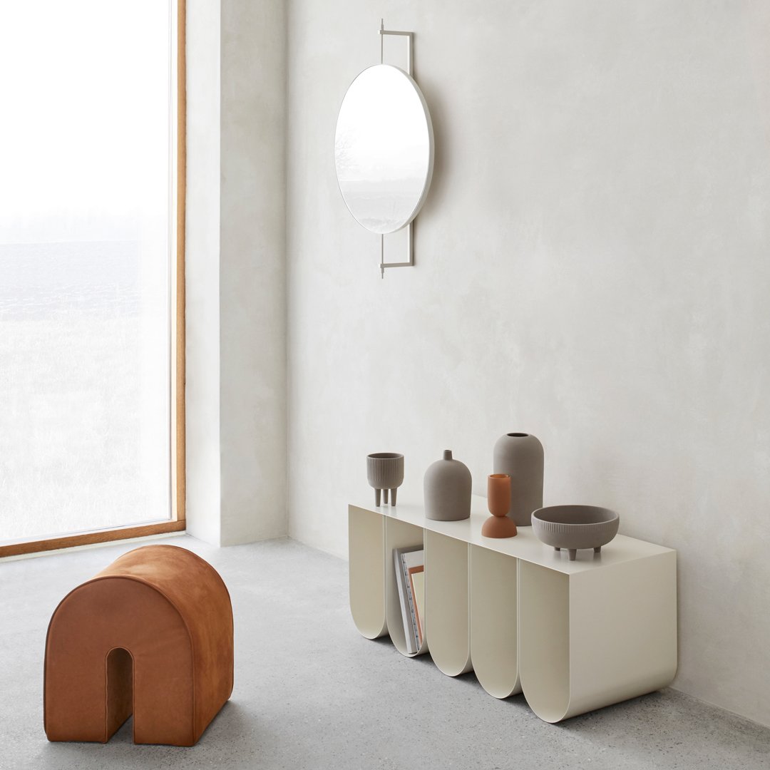 Minimalist furniture in beige and terracotta, featuring smooth curves and simple silhouettes against a light gray backdrop.