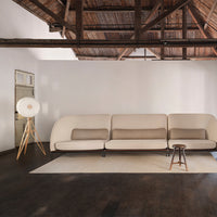 Beige sofa with brown cushions, soft cream rug, and dark wooden floor against a white wall and rustic ceiling.
