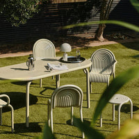 Light beige outdoor table and chairs with textured ribbed patterns, set on green grass. Modern and stylish design.