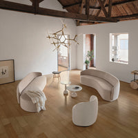 Elegant beige curved sofas and textured white cushions, set against warm wood flooring and a minimalist backdrop.
