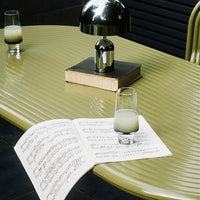 Stylish olive green tabletop with glossy, ribbed texture and reflective silver lamp, accentuated by clear glassware.