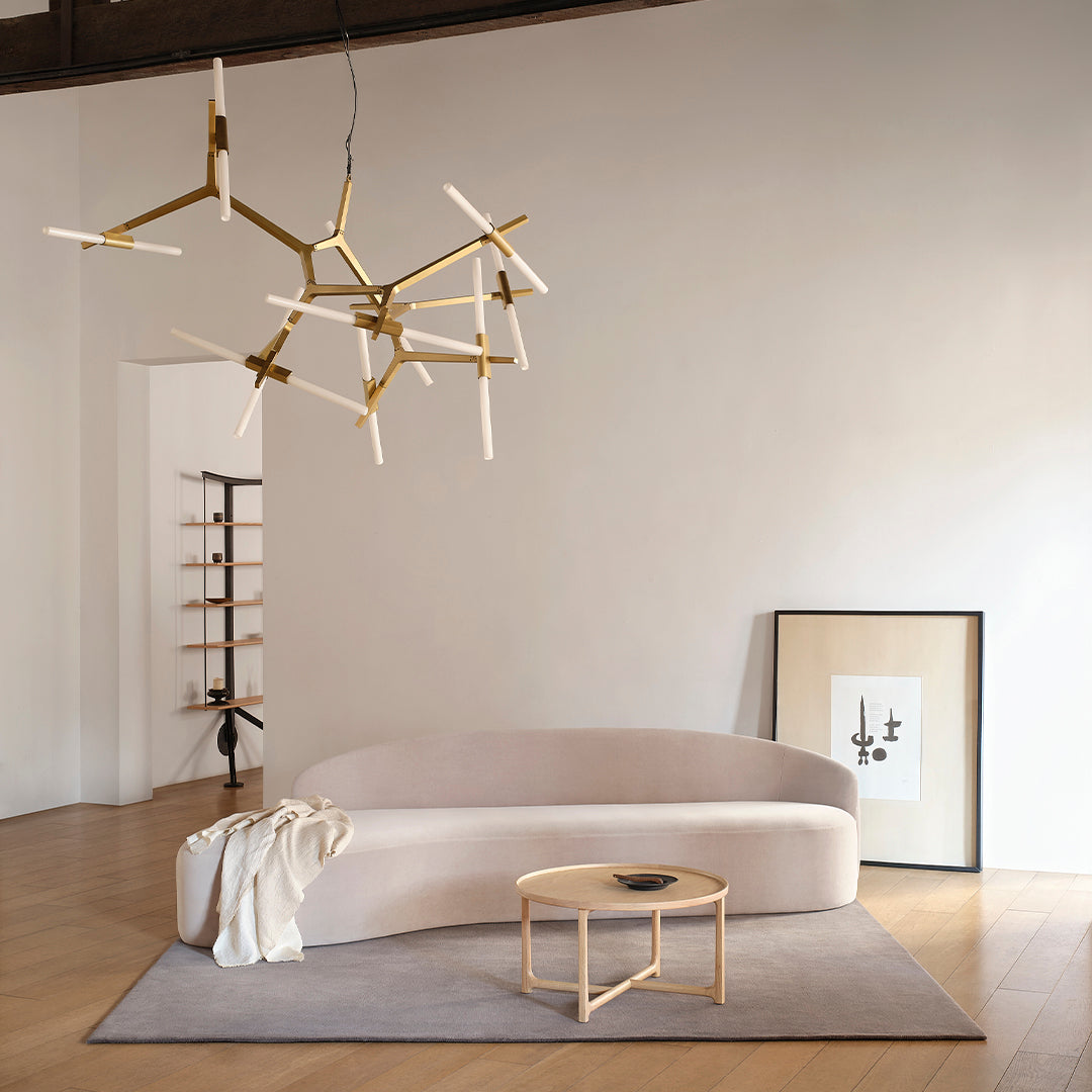 Modern chandelier with gold accents and white light fixtures, complementing a soft beige sofa and neutral decor.