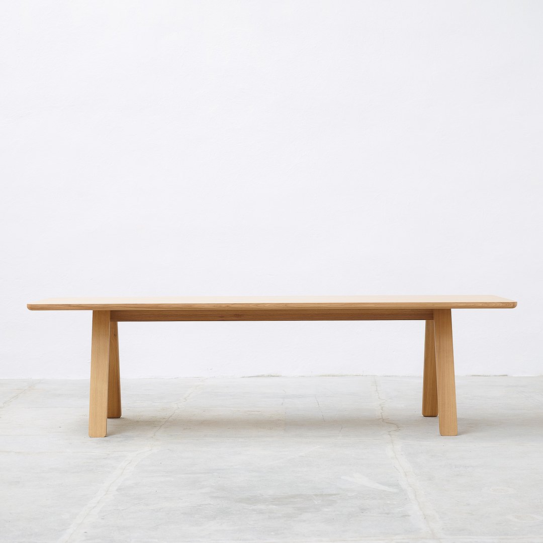 Light wooden table with a smooth surface and minimalist design, featuring natural grain patterns and clean lines.