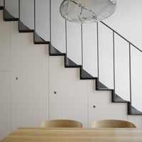 Modern staircase with black steps and white walls, featuring a minimalist design and subtle geometric patterns.