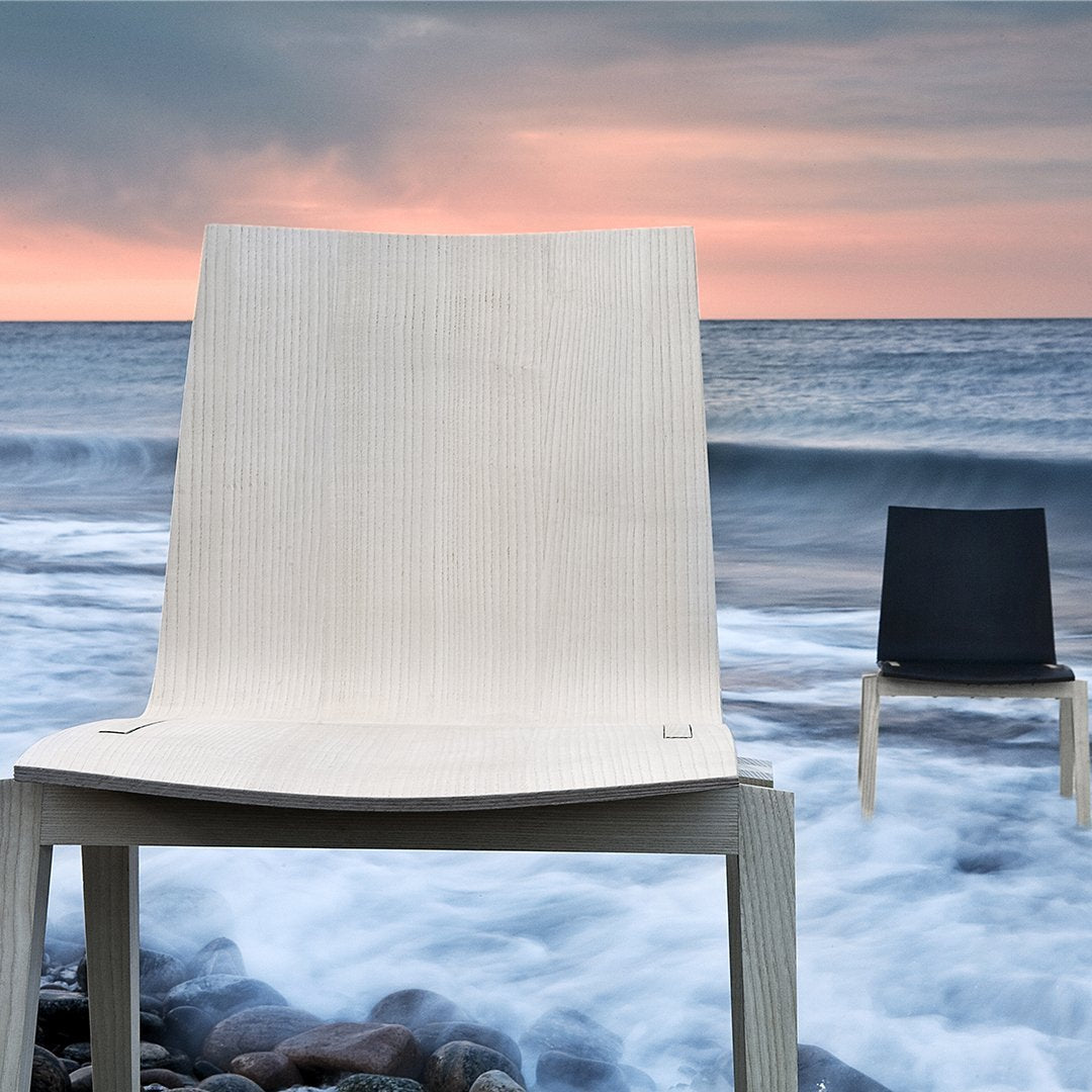 Light beige and deep black chairs against a beach backdrop, featuring textured patterns and smooth lines.