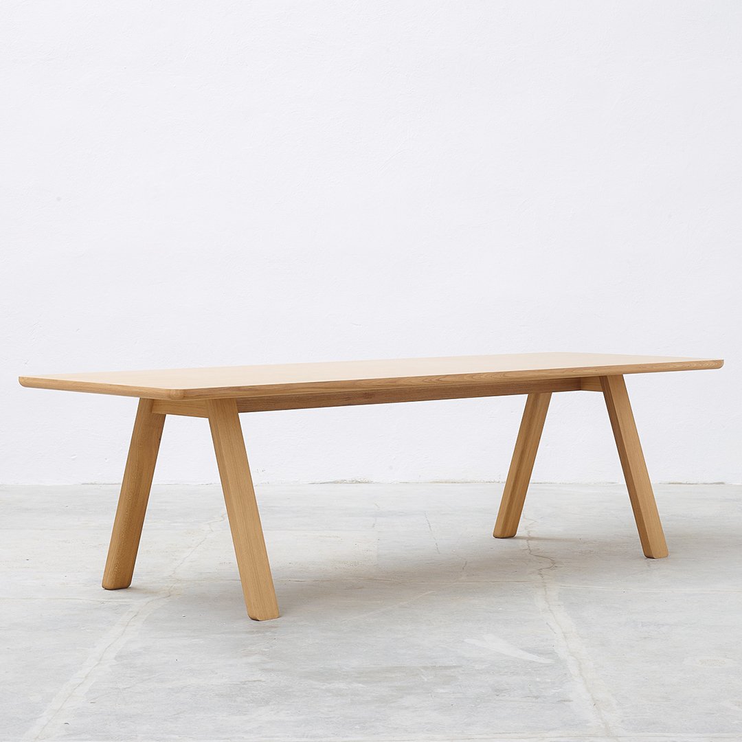 Natural wood table with a smooth finish and minimalist design, featuring light brown tones and clean lines.