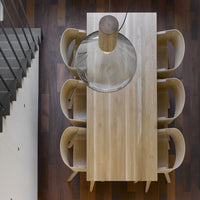 Light wood dining table with smooth finish, surrounded by curved, light-colored chairs on rich brown wooden flooring.