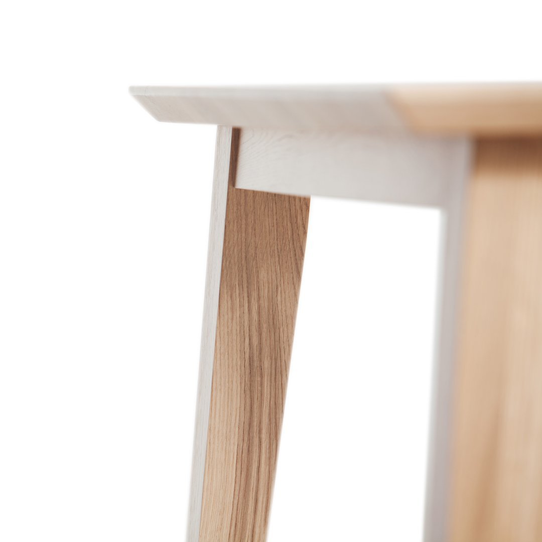 Close-up of a modern table with a light wood grain finish and a sleek white tabletop, highlighting natural textures.
