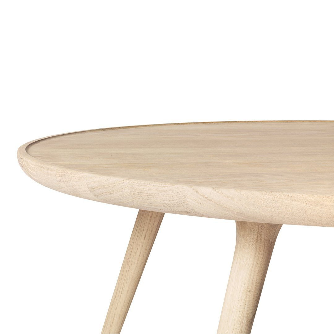 Light oak round table with smooth edges and natural wood grain texture, complemented by tapered, pale wooden legs.