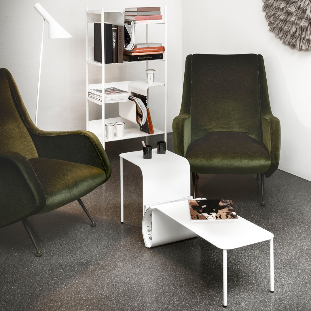 Green velvet chairs paired with a sleek white coffee table on dark gray flooring. Minimalist design with modern vibes.