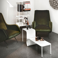 Green velvet chairs paired with a sleek white coffee table on dark gray flooring. Minimalist design with modern vibes.