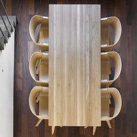Light wooden table with a smooth finish, complemented by soft beige chairs against a rich dark wood floor.