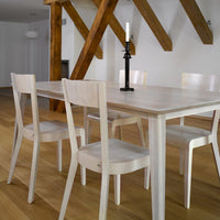 Elegant white dining table with sleek chairs, complemented by warm wooden beams and a soft natural wood floor.