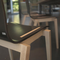 Sleek black chair with smooth curves and a light wood base, perfect for modern decor.