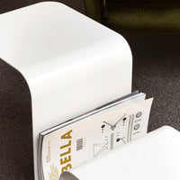 White curved magazine holder displaying minimalist design and sleek surface, set against a dark textured background.