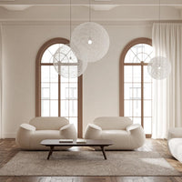 Cream-colored bean bag chairs with textured patterns, set against warm wood tones and soft white curtains.