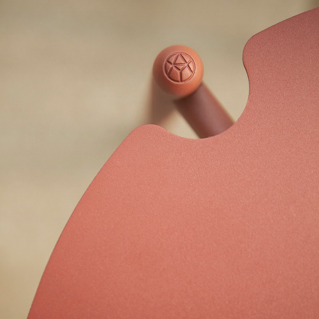 Rust-orange round table edge with a textured peach accent and soft curves against a neutral background.