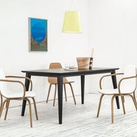 Black dining table with smooth surface, paired with white and natural wood chairs, featuring a vibrant blue wall art.