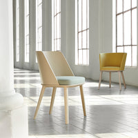 Light beige and soft mint chair with wooden legs; bright yellow accent chair in a spacious, airy setting.