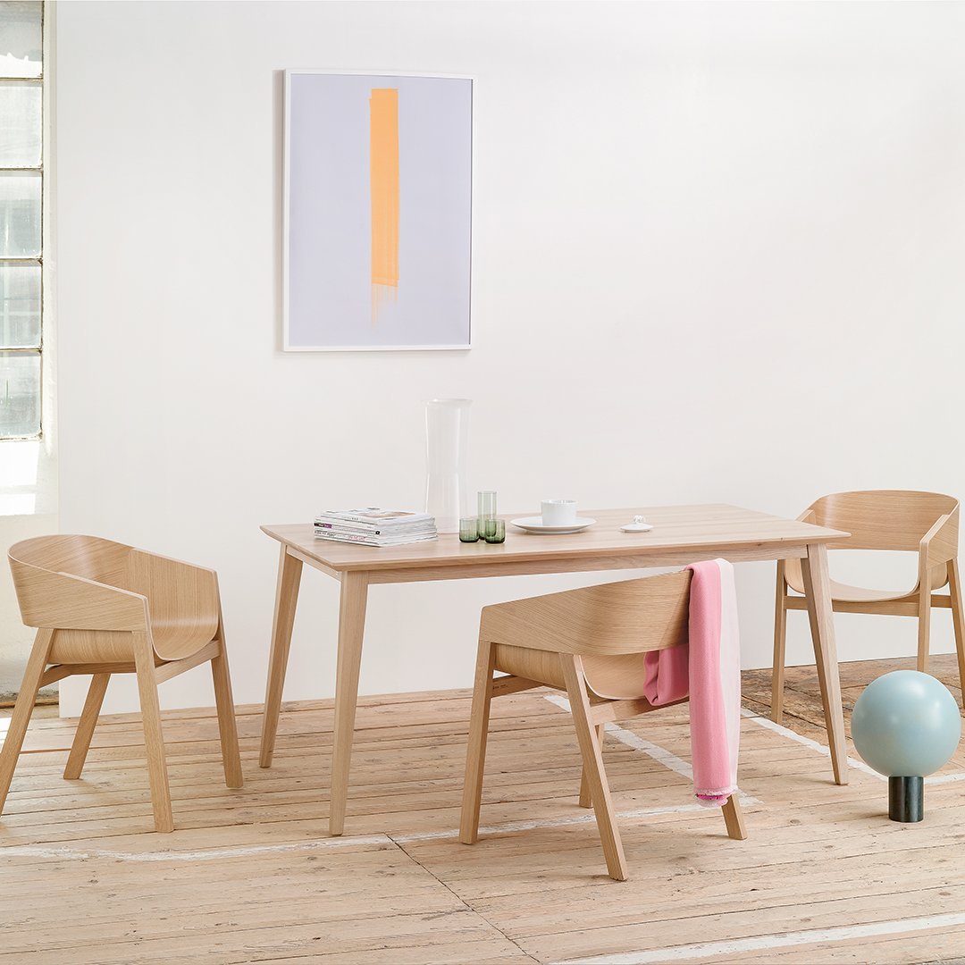 Light wood dining table with pastel pink, orange, and blue accents, featuring clean lines and minimalistic design.