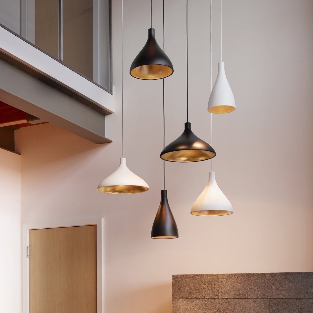 Five pendant lights in black, white, and gold, featuring smooth and textured finishes, suspended from the ceiling.