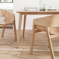 Light wooden dining table and chairs with smooth, natural grain finish, set on a warm wooden floor.