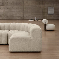 Curved cream-colored sofa with a textured, boucle fabric, set against a minimalistic, modern backdrop.