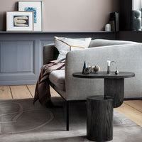 Gray sofa with geometric throw pillow, dark wood accent table, and soft beige carpet featuring a subtle pattern.