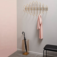 Stylish gold wall hook with soft pink accents, against a light gray and blush pink backdrop. Modern and minimal design.