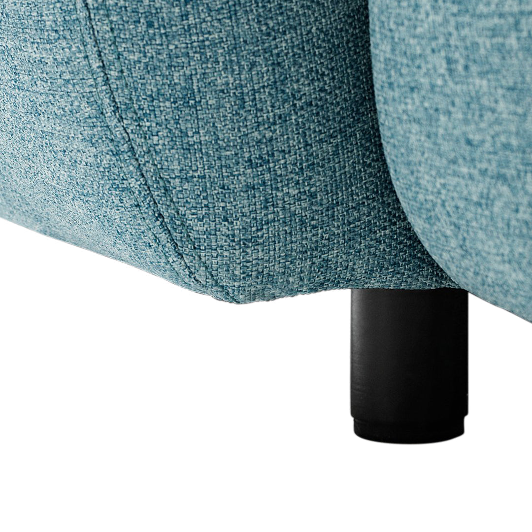 "Close-up of textured blue fabric with subtle patterns, featuring a sleek black leg."