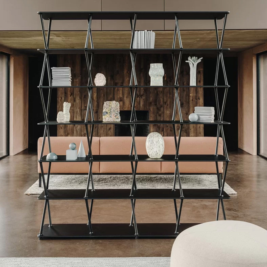 Black geometric bookshelf with triangular patterns and sleek design, set against a warm wood wall and modern decor.