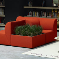 "Vibrant orange sofa with modern design, featuring geometric shapes and a built-in planter with lush greenery."