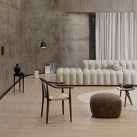 Cream-colored curved sofa and natural wood furniture in a minimalist, modern living space with warm earthy tones.