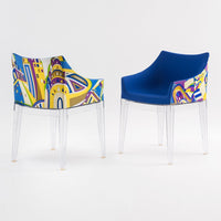 Colorful patterned chair featuring blue upholstery and vibrant abstract designs in yellow, red, and green. Transparent legs.