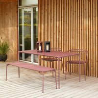Modern outdoor furniture set in soft pink with sleek lines, paired with black lanterns against a wooden backdrop.