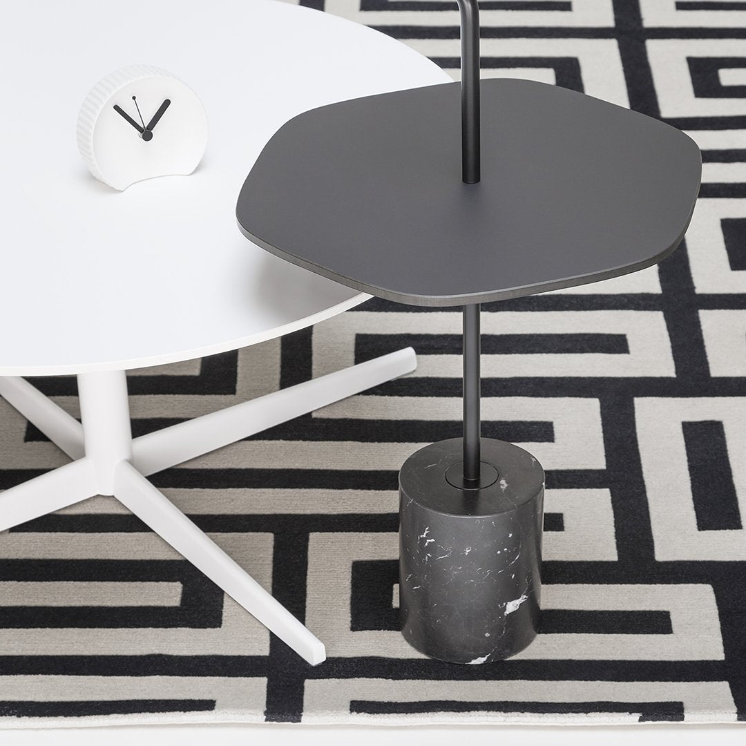Modern black and white geometric patterned rug with a sleek black side table and white round coffee table.