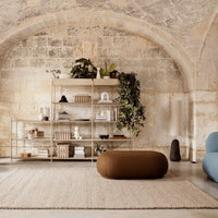 "Modern living room: neutral tones, earthy brown ottoman, blue accents, and organic textures in a soft, serene space."