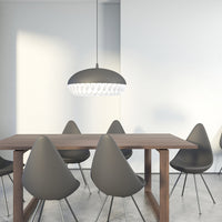 Gray pendant light over a minimalist wooden table with rounded gray chairs, set against a bright, clean backdrop.