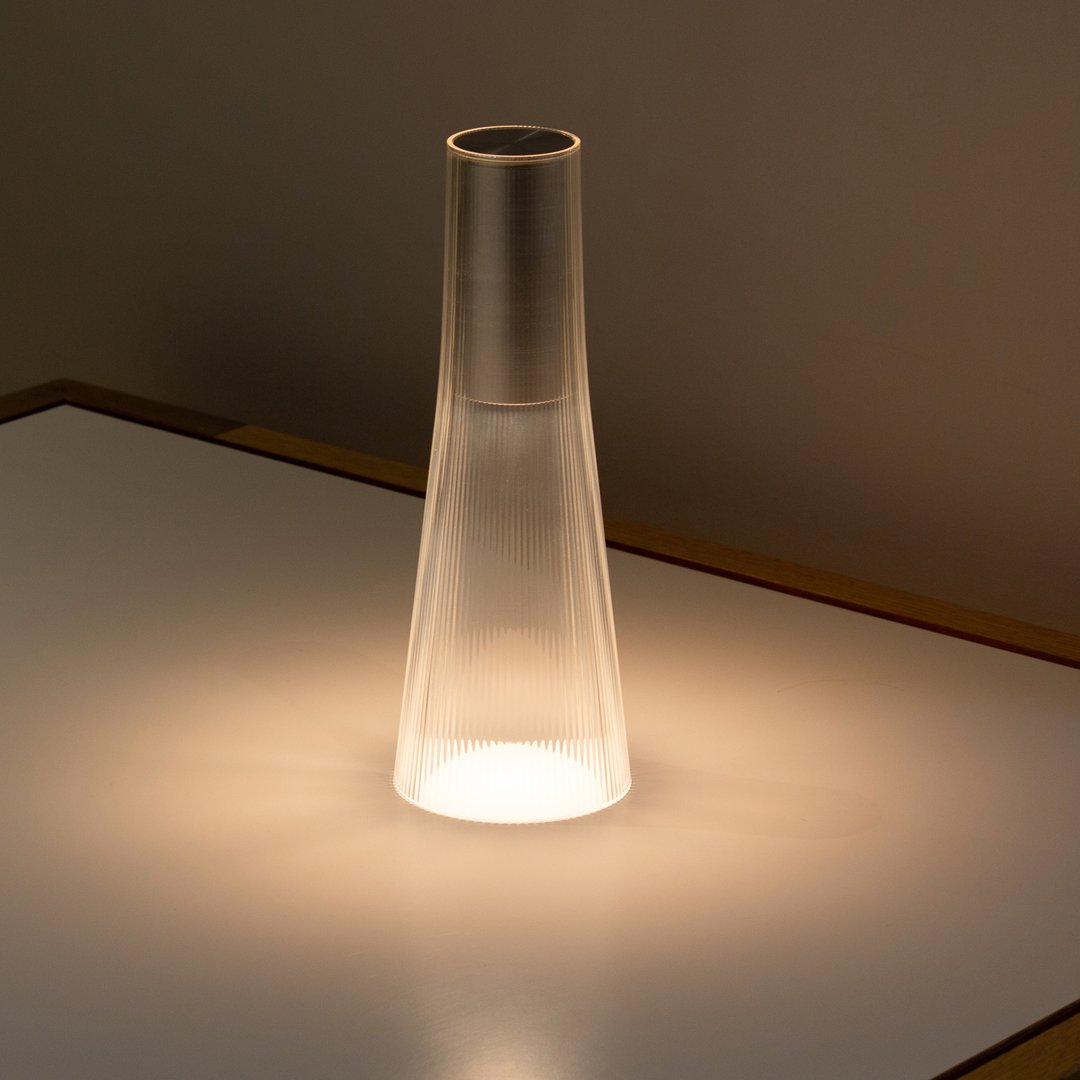 Frosted glass lamp with a sleek silver top, softly illuminating a modern, minimalist design.