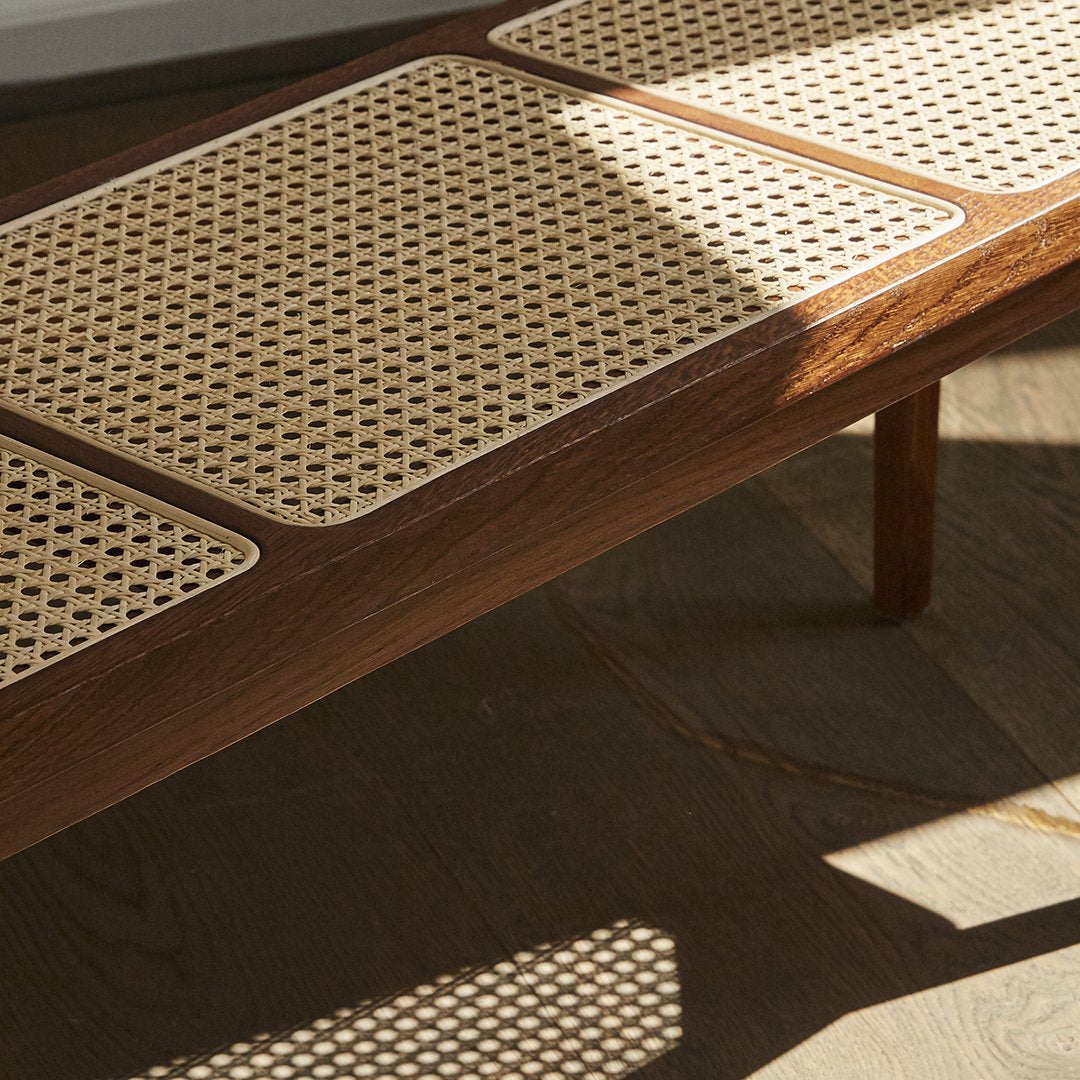 Wooden table with a light cane pattern top, featuring rich brown tones and natural textures. 