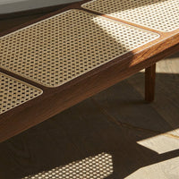 Wooden table with a light cane pattern top, featuring rich brown tones and natural textures. 