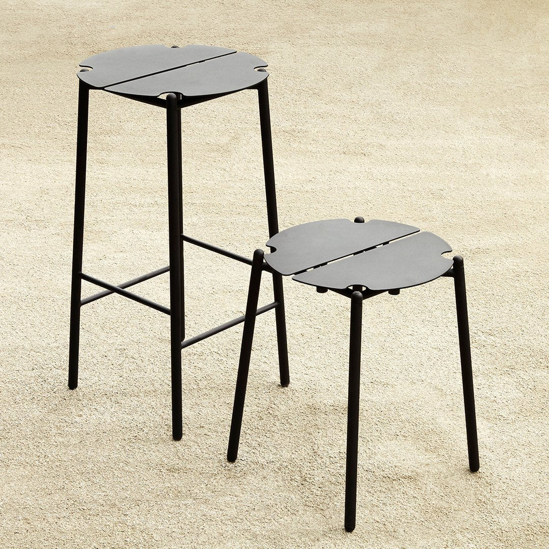 Set of two black metal stools with a minimalist design and circular, slotted tops. Ideal for modern decor.