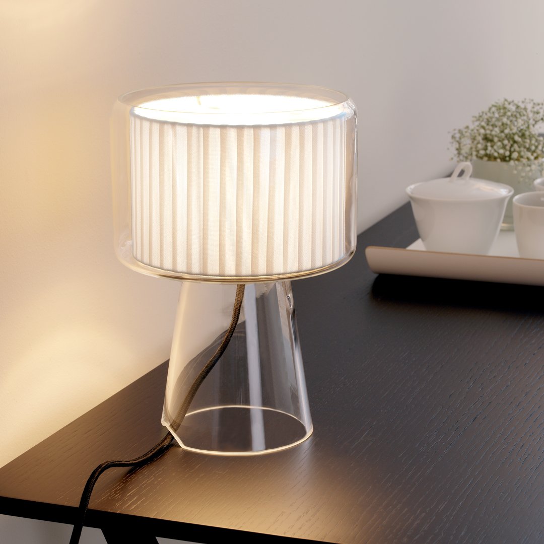 Clear glass lamp base with a white pleated shade, creating a modern and elegant lighting accent for any space.