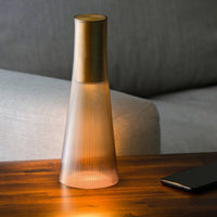 Gold-accented glass lamp with a ribbed texture and warm, soft light, set on a wooden surface.