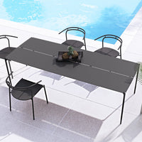 Modern black outdoor dining table with sleek lines, paired with minimalist black chairs beside a pool.