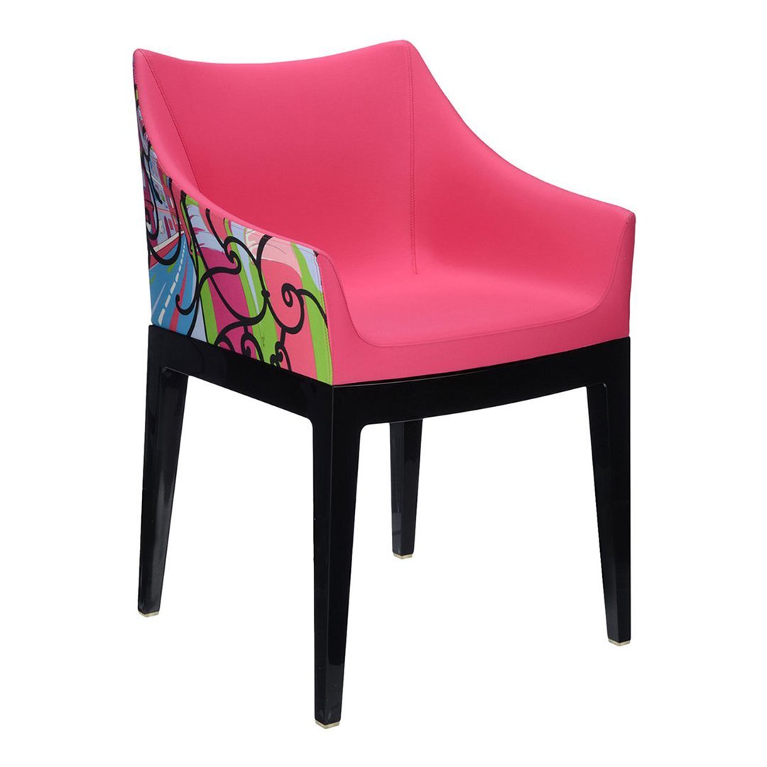 Bright pink chair with colorful floral and abstract patterns on the side, complemented by sleek black legs.