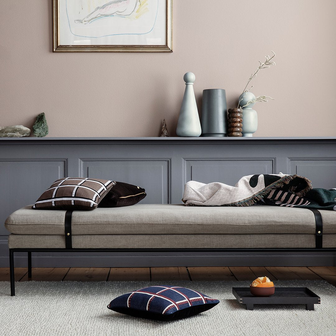 Neutral beige and gray tones with black, checkered, and solid-patterned pillows on a minimalist daybed.